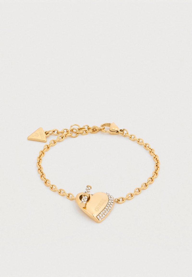 Βραχιόλι από χρυσό με γοητεία σε σχήμα καρδιάς με κούμπωμα και κρυσταλλικά διακοσμητικά. Οι κρίκοι είναι κυκλικοί, δημιουργώντας μια υφή εμφάνιση.