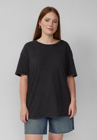 Overmaat zwart katoenen t-shirt met korte mouwen, ronde hals en zichtbare stiksels, gecombineerd met denim shorts.