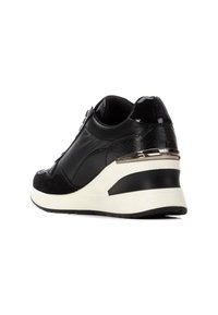 Sneaker noir avec un mélange de cuir lisse et de matériaux texturés, au design épuré, avec une semelle contrastée blanche et noire et des accents métalliques.