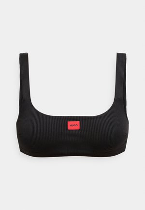 Juoda briaunuota liemenėlė su kvadratiniu iškirpimu ir plačiomis petnešėlėmis. Priekyje yra raudonas stačiakampis lipdukas su užrašu „HUGO“. Minkšta tekstūra.