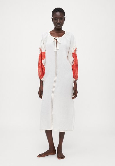 Weißes Leinenkleid mit roten floral gemusterten Ärmeln, lang geschnitten, runder Ausschnitt und vorderem Bindedetail; mit dezenten braunen Stickerei-Akzenten.