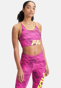 Rosa atletisk croptop och höga leggings med grafiskt mönster och neongula detaljer. Designad för aktiv träning med en figurnära silhuett.