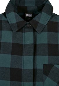 Chemise en flanelle à carreaux verts et noirs avec col boutonné, étiquetée Urban Classics XS, fabriquée en Chine.