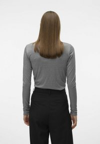 Haut gris à manches longues avec un design ajusté, associé à un pantalon noir taille haute, vu de dos sur un fond neutre.
