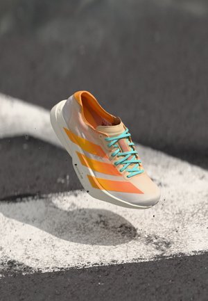 A single running shoe with orange and light blue accents appears to levitate above a white pedestrian line on a dark surface.