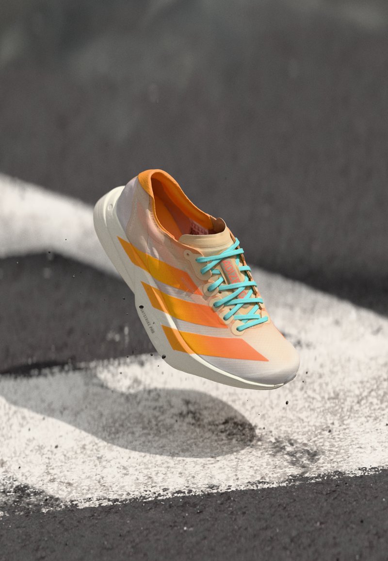 A single running shoe with orange and light blue accents appears to levitate above a white pedestrian line on a dark surface.