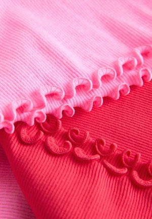 Due pezzi di tessuto a righe, uno rosa chiaro e uno rosso, con bordi arricciati decorativi. Le trame sono lisce ed elastiche.