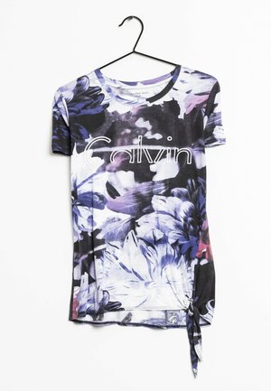 T-shirt a fantasia floreale nei colori viola, nero e bianco. Presenta un collo rotondo, maniche corte e un dettaglio a nodo sull'orlo. Logo "Calvin" in bianco.