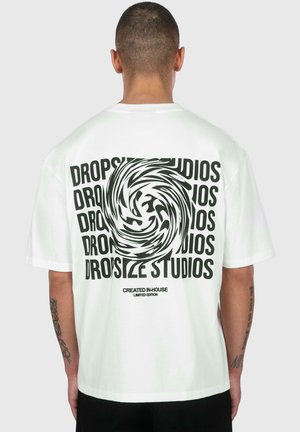 Hvid t-shirt med en stor sort cirkulær grafik og "DROPSIZE STUDIOS" trykt flere gange. Korte ærmer, afslappet pasform, made af bomuldsstof.