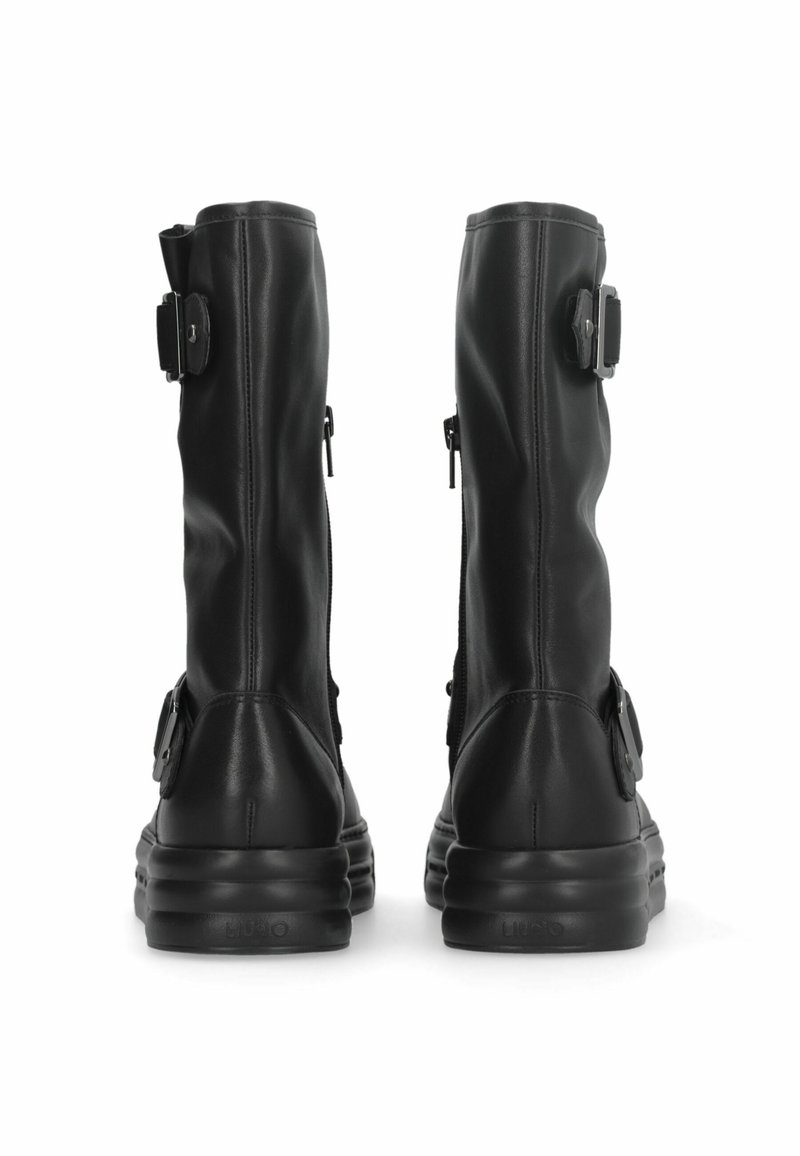 Schwarze Lederstiefel mit hohem Schaft, seitlichen Reißverschlüssen und verstellbaren Schnallenakzenten am Knöchel. Rund, gepolsterte Sohle.