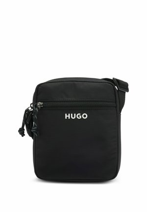 Kompakte schwarze Umhängetasche mit vorderer Reißverschlusstasche, verstellbarem Riemen und "HUGO"-Logo in weißen Buchstaben auf der Vorderseite.