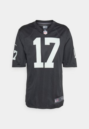 Homme portant un maillot noir NFL numéro 17, un pantalon de survêtement gris clair et des chaussures de sport noires, debout devant un fond blanc uni.