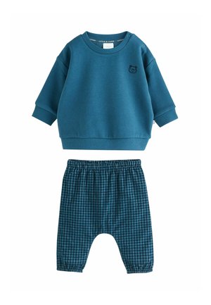 Turkusowy sweatshirt z małym haftowanym misiem na piersi, zestawiony z lekkimi spodniami w kratę z elastycznym pasem.