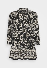Blouse à manches longues à motif noir et blanc avec une coupe décontract�ée, dotée d'un ourlet à volants et d'une fermeture à boutons ; fabriquée en tissu léger.