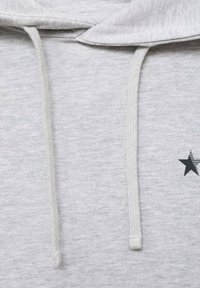 Sweat à capuche gris avec cordon de serrage. Présente un motif d'étoile noire sur la poitrine. Le matériau semble doux et texturé.