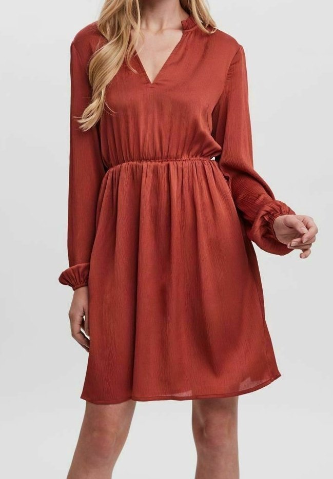 Robe couleur rouille avec un décolleté en V, des manches longues, une taille élastique et des poignets à volants. Le tissu a un design texturé et fluide.