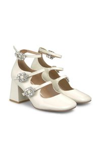 Chaussures en cuir verni blanc à talons carrés, avec deux brides réglables à la cheville, ornées de boucles en bijou décoratives et dotées d'un design à bout arrondi.