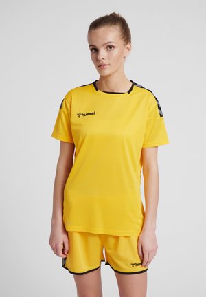 Maglietta sportiva gialla con accenti neri e logo, abbinata a pantaloni corti coordinati. Realizzata in tessuto traspirante, presenta un design semplice e atletico.