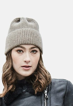 Grey knit beanie with ribbed texture, featuring a folded cuff and subtle sheen. Worn with a black leather jacket, showing a close-up view.