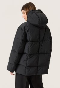 Svart pufferjacka med huva, med en vadderad design och en avslappnad passform. Slät textur med en matta finish.