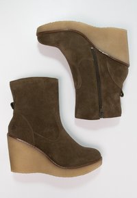 Stivaletti con zeppa in camoscio marrone con finitura testurizzata, cerniera laterale, punta arrotondata e suola piattaforma beige spessa.