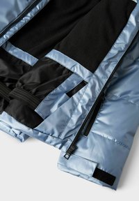 Plava zimska jakna s crnim flis unutrašnjim dijelom, crnom elastičnom trakom u struku, zatvaračem i prilagodljivim čičak manžetama, prikazana djelomično otvorena.