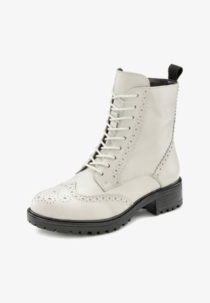 White leather ankle boot with lace-up design, brogue detailing, round toe, and textured black rubber sole for traction.