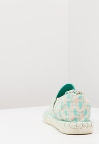 Scarpa espadrille slip-on con un tessuto crema testurizzato, caratterizzato da un motivo astratto turchese e una suola in juta intrecciata. Vista posteriore mostrata.