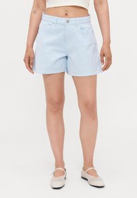 Shorts rayés bleu clair, en denim, design ajusté, longueur mi-cuisse, avec poches avant et fermeture à bouton à la taille.