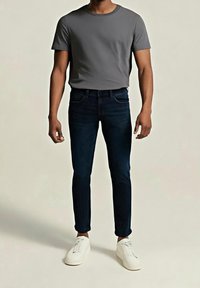 Camiseta de algodón gris, vaqueros ajustados azul oscuro y zapatos blancos. La tela es suave y el denim tiene un ligero grado de elasticidad.