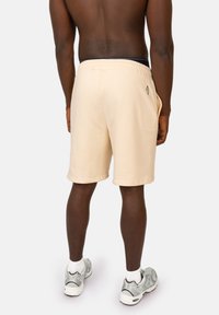 Beige katoenen shorts met een elastische tailleband en zijzakken, met een klein logodetail boven de rechterzak.