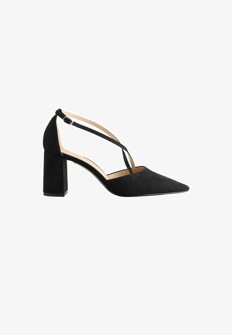 Chaussure à talon bloc en daim noir avec bout pointu et fines brides de cheville croisées sur le pied, maintenues par une petite boucle sur le côté.