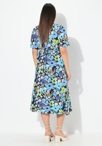 Květinové midi šaty s krátkými rukávy, se černým pozadím, modrými, zelenými a bílými květy a uvázaným pasem pro přiléhavý siluetu.