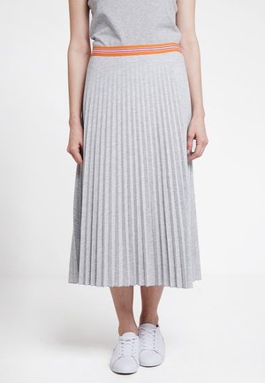 Grå plisseret midi-nederdel med en livlig orange og hvid stribet taljebånd, lavet af blødt stof, kombineret med hvide sneakers.