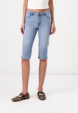 Light blue denim bermuda shorts with a fitted waist, mid-thigh length, rolled cuffs, and front and back pockets. Worn with leopard print flats.