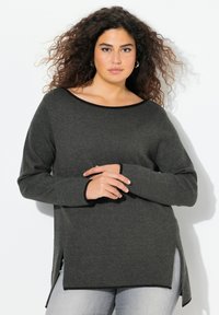 Pull en tricot gris foncé avec un décolleté large, des poignets côtelés et des fentes latérales. Présente des finitions contrastantes noires le long du décolleté et de l'ourlet.