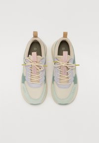 Baskets légères avec un corps en mesh beige et des accents vert menthe et violet pâle, ainsi qu'une semelle texturée. Comprend des lacets crème et un onglet de talon rose.