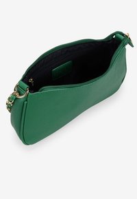 Bolsito de mano de piel verde con cierre de cremallera, acabado texturizado y herrajes dorados. El interior es de tela negra con una pequeña etiqueta visible.