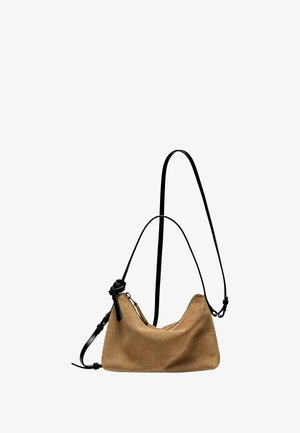 Zamszowa torebka w jasnobrązowym kolorze o zaokrąglonym kształcie, czarny regulowany pasek, kontrastowy zamek oraz miękka tekstura.