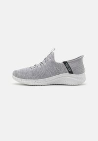 Chaussure de sport gris clair avec une tige texturée, sans lacets, et une semelle intermédiaire blanche avec des éclaboussures. Elle possède un onglet noir au talon pour un enfilage facile.