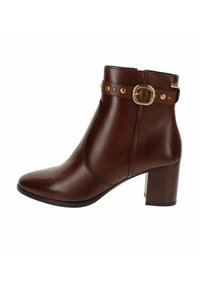 Stivaletto in pelle marrone con tacco largo, fibbia decorativa in oro e borchie sul cinturino, chiusura con zip laterale.