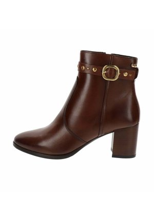 Stivaletto in pelle marrone con tacco largo, fibbia decorativa in oro e borchie sul cinturino, chiusura con zip laterale.