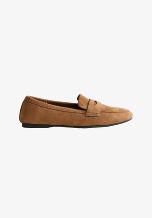 Mocasín plano de ante marrón con una correa en la parte superior y una suela negra, mostrado de perfil sobre un fondo blanco.