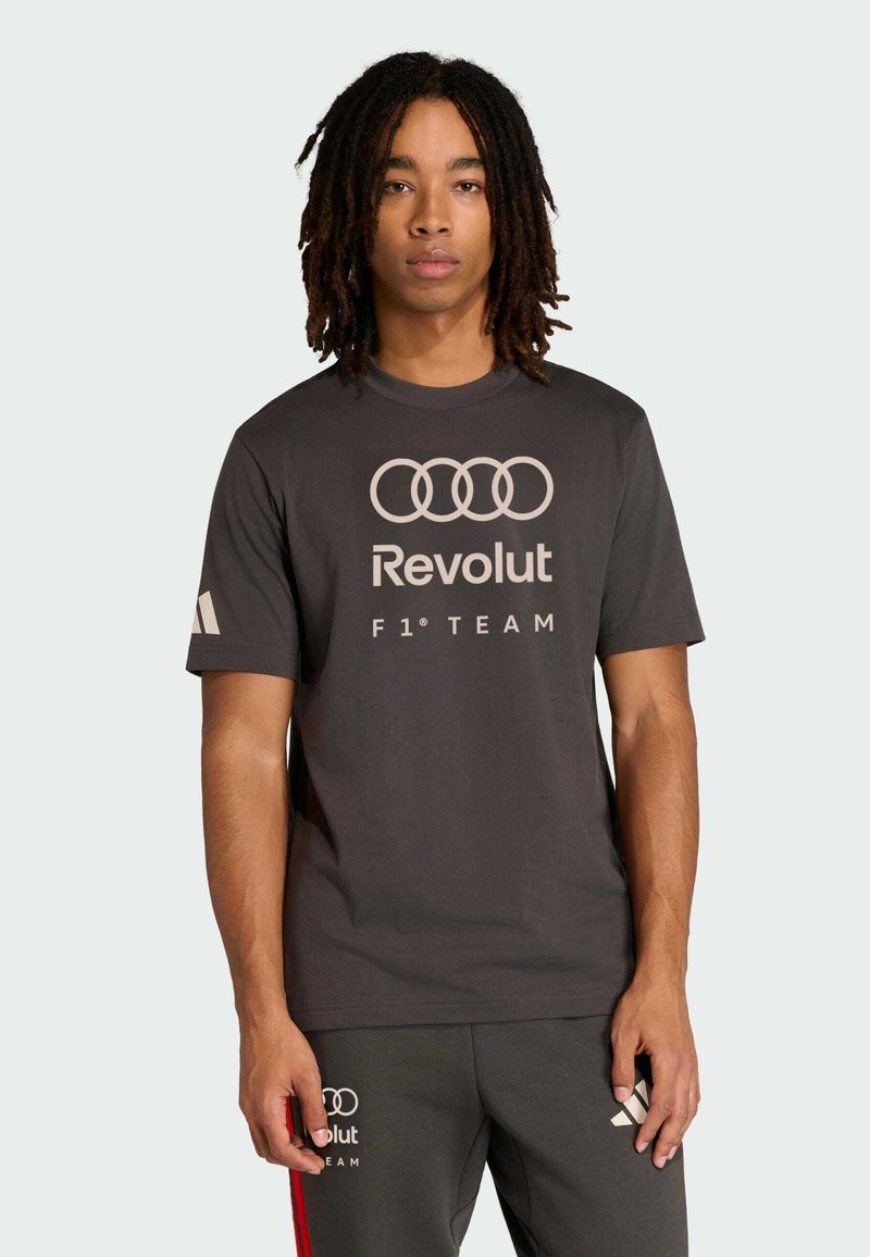 Grijs T-shirt met korte mouwen en een ronde hals, met witte Audi-ringen en "Revolut F1 TEAM" gedrukt op de voorkant. Gladde stof, losse pasvorm.