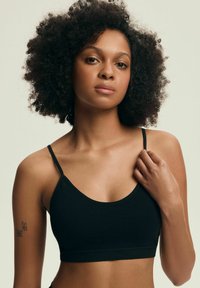 Czarny stanik sportowy z regulowanymi cienkimi ramiączkami, gładką teksturą i dopasowanym krojem, przedstawiony na jasnym tle.
