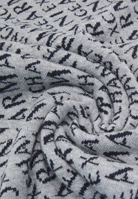 Pletená sivá tkanina s námorníckymi abstraktnými vzormi, predvádzajúca jemný, textúrovaný povrch a hladké, kruhové prehnutie.