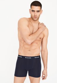 Bóxer para hombre de color azul marino, hecho de un material suave, con una cinturilla negra que lleva el logo de "Resteröds", y un diseño de ajuste ceñido.