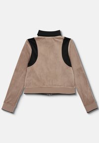 Brun velourjakke med sorte skulderpaneler, lynlås lukning og ribbede manchetter. Har en høj krave og cropped design. Glat tekstur.