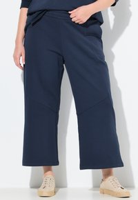 Marina vida byxshorts med elastisk midja, sidofickor och kontrasterande sömmar. Matchas med ljust färgade, texturerade sportskor.