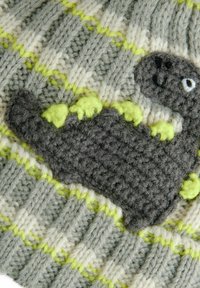 Accessoire tricoté mettant en avant un motif de dinosaure gris avec des accents verts vifs, sur un fond texturé de gris et crème, avec des touches de vert éclatant.